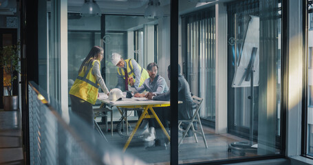 Executives and Engineers Meet in a Glass Office to Plan a Construction Project, Review Drawings and Reports, Align Schedule and Budget, Discuss Safety and Quality © Gorodenkoff