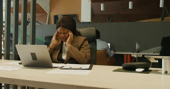 Female employee focused on paperwork beside her computer in office