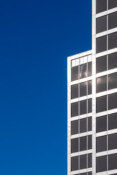 Geometric grid on modern minimal architecture tower facade shows blue sky detail creating clean urban highrise backdrop for design projects