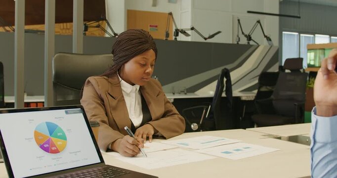 Professional in office annotating colorful financial charts attentively