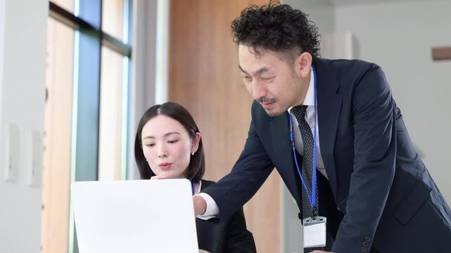 パソコン業務を指導する上司と社員のOJT研修などの社員教育のイメージ　先輩に指導を受ける若手社員の成長と教育のビジネスシーンの動画