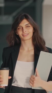 Successful woman in business suit walking confidently in office building with tablet and coffee showing motivation empowerment success mindset modern female leader career ambition independence power