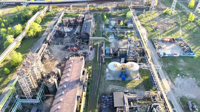 Aerial view of industrial plant showing continuous operations with pipelines, storage tanks, and machinery in a green landscape, highlighting the interconnected processes of manufacturing and producti