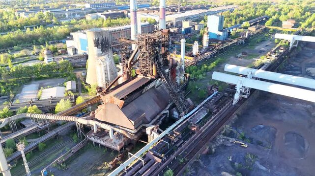 Aerial view of industrial plant showing continuous operations with pipelines, storage tanks, and machinery in a green landscape, highlighting the interconnected processes of manufacturing and producti