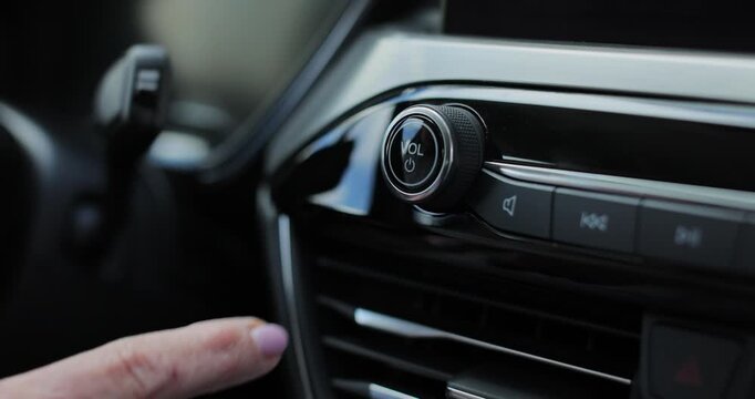 Woman turning on the car radio, driver pressing button of to listening music or radio broadcast.