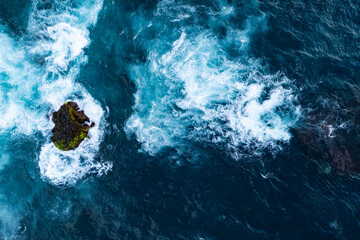 Waves hitting volcanic rocks and shallow reef, aerial top down view © Leonid