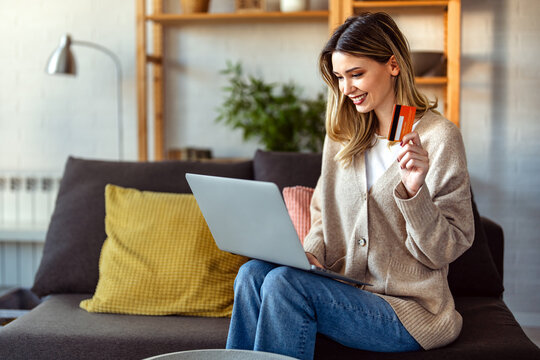 Young woman making an online payment with a credit card and laptop at home, cashless lifestyle