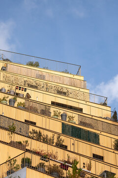 Sunlight on a modern residential architecture facade with terrace and plants above urban Paris France creating warm apartment layers