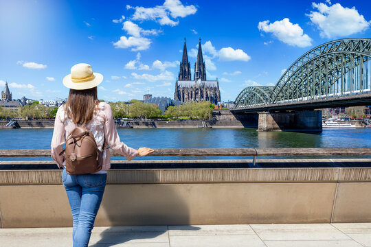 A tourist woman looks at the River Rhine and Cathedrale of Cologne, Germany, during her sightseeing tour through the City