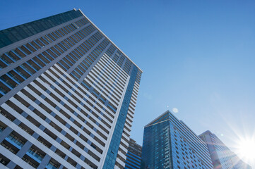Fototapeta premium Modern high-rise residential buildings with glass facades against a clear blue sky.