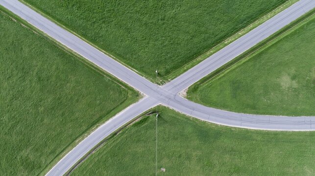 Aerial view of rural asphalt road intersection in green fields