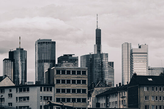 Dramatic overcast frankfurt skyline with modern skyscraper tower rising above urban city rooftops showcasing architecture in moody light