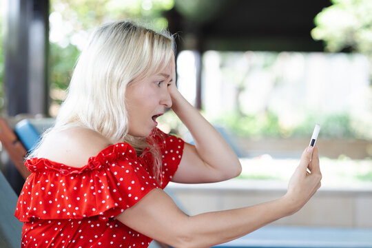 Angry and Frustrated Middle aged Caucasian aunt, aged woman using smartphone, negative expression, concept image for slow connection, internet scam, internet fraud, poor cyber security