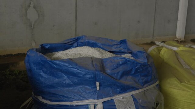 Open bulk bag containing white recycled plastic pellets inside industrial recycling facility