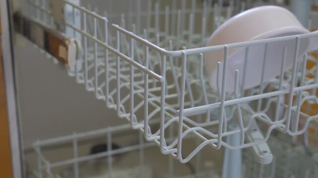 Emptying the remaining dishes from a dishwasher.