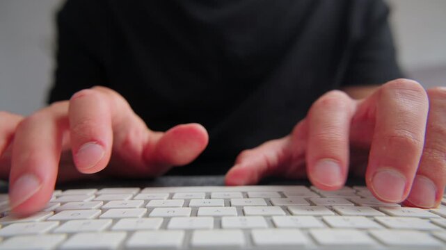 Person's hands swiftly typing on a white computer keyboard, creating digital content, working, or communicating online.