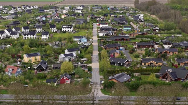 Drone view of eco village Bolderburen between Almere and Zeewolde, showing wooden homes, gardens, orchard, Scandinavian style, and sustainable community living.