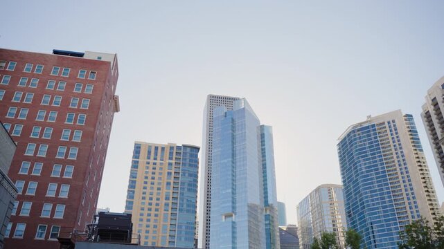 Street level panoramic view of Downtown Houston skyline featuring modern office towers and urban architecture, filmed with left to right camera motion from a parking lot during daytime in Houston, Tex