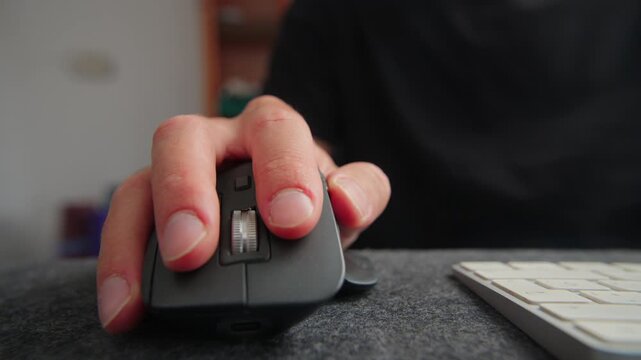 Hand browsing with a modern ergonomic computer mouse and keyboard on a felt desk mat, illustrating digital work.