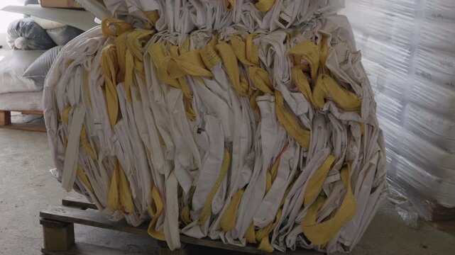 Compressed bale of discarded woven polypropylene bags on pallet inside recycling warehouse