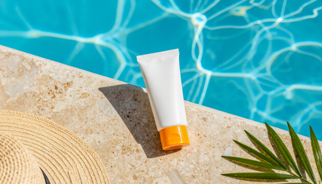 Crema solare e cappello di paglia a bordo piscina con foglia di palma