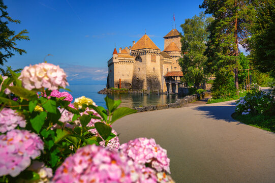 Montreux, Switzerland - July 2, 2024 : Historic Chillon Castle on the shore of Lake Geneva near Montreux, Switzerland, with flowers and a lakeside path.