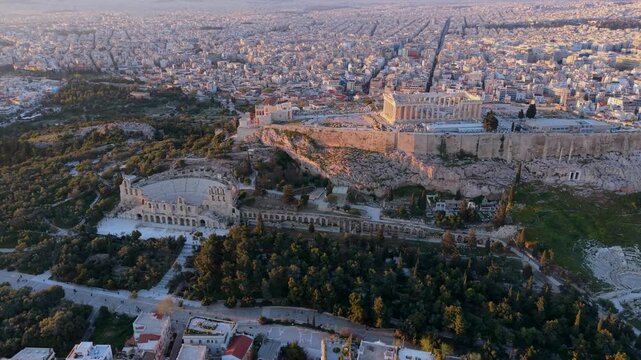 Aerial Video of the Acropolis, Parthenon, and Odeon of Herodes Atticus, set against the vast Athens cityscape during golden hour.