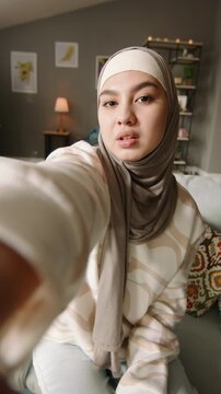 Confident woman in hijab capturing selfie with hand near face showing healthy clear skin minimal beauty style soft happy mood wellness confidence and modern digital lifestyle self love moment