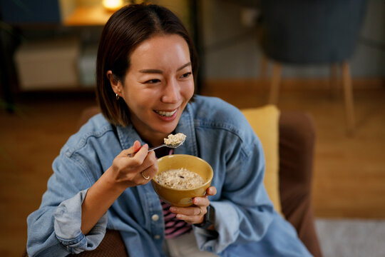 Woman enjoying breakfast with spoon while relaxing at home