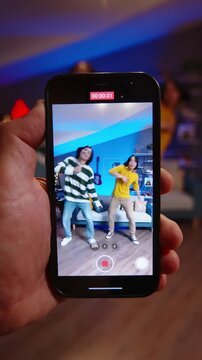 POV shot of smartphone filming synchronized dance performance by Asian teen boys creating influencer style social media content in modern home interior