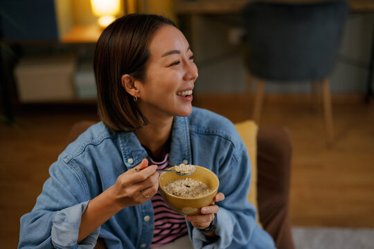 Woman eating healthy oatmeal breakfast smiling at home
