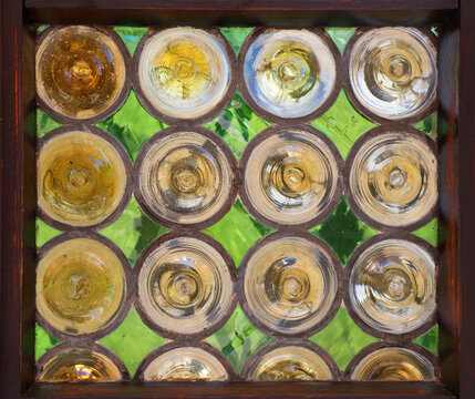 Abstract vintage tainted glass block window with circular patterns and green background. Close-up traditional texture of decorative glass panel framed in dark wood. Ideal for background, banner.