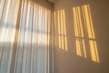 Obraz premium Curtains cast long shadows on a wall, illuminated by golden sunlight.