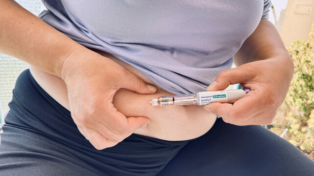 Woman injecting medication pen into abdomen for diabetes management and weight loss