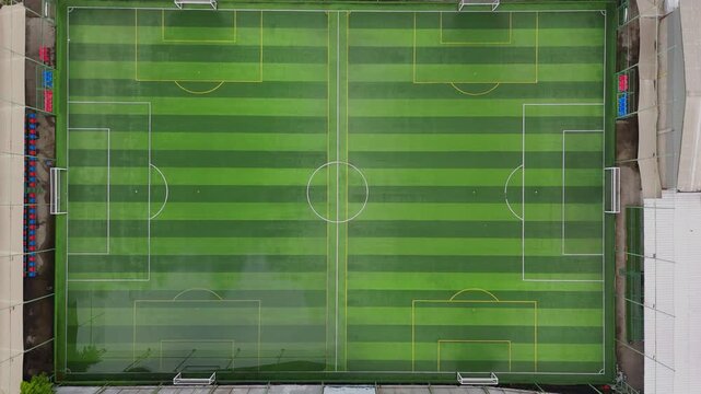 Top down aerial shot of an empty futsal court with green artificial grass and white boundary lines