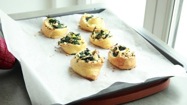 Freshly baked golden puff pastry appetizers with spinach and cheese on a baking tray