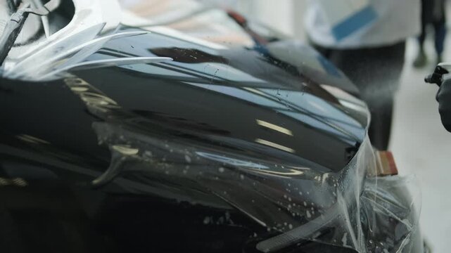 Close Up of Professional Detailer Applying Transparent Paint Protection Film on a Car Hood