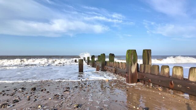 Close up view of wooden sea breakers on the Norfolk Coast. 2 x slow motion Static shot