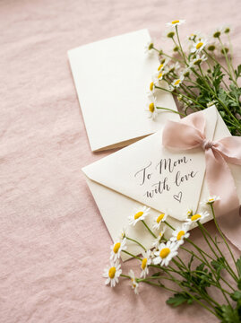 Mother's Day card envelope with daisies and pink ribbon on blush