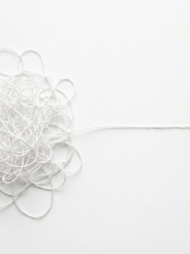 Tangled white thread unraveling into straight line, minimal concept