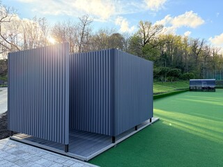 a outdoor modern locker room or shelter situated on the edge of an artificial turf soccer field. © Vovmar