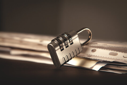 Padlock on a pile of papers on a dark background, security concept