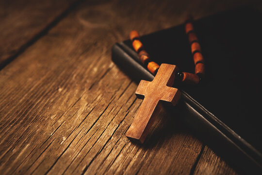 Wooden cross and bible on a wooden background. Religion concept.