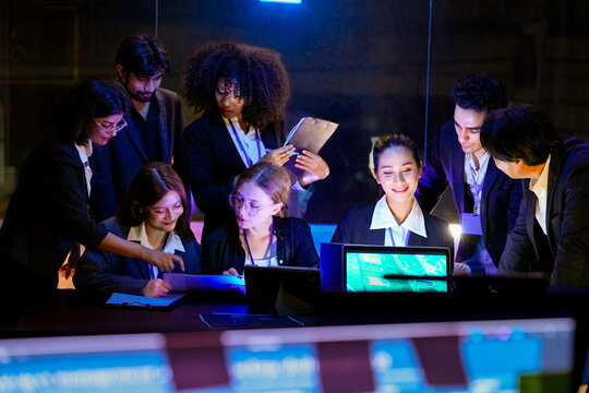Multiethnic technical experts gathering for a strategic meeting in a futuristic high-tech command center. Dedicated team evaluating system infrastructure and business growth under blue neon light.