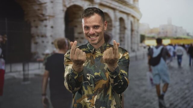Man soldier in camouflage shirt showing finger heart with both hands on street by the colosseum among tourists; pride duty.