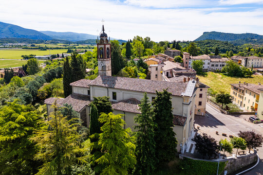 Historic church building and small town center with surrounding countryside and farmland in Costermano sul Garda, Italy, aerial view