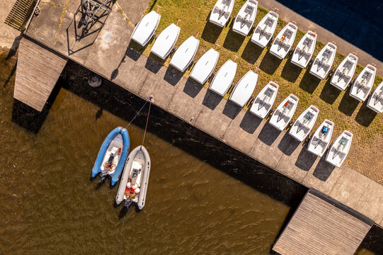 Diagonal aerial top down view of a boat dock with sailing dinghies and motorboats
