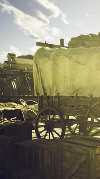 A vintage wagon rests among wooden crates, basking in the golden sunlight. The background features distant structures, hinting at a lively history and a serene natural landscape.