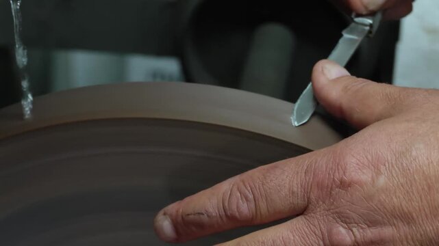 Professional Knife Sharpening in 4K Slow Motion &ndash; Close-Up of Craftsman Honing Folding Knife Blade on Rotating Sharpening Stone, Precision Blade Maintenance Workshop