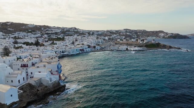 Mykonos island traditional whitewashed homes on the Aegean sea shore overlooking Little Venice, famous windmills in view, Drone shot